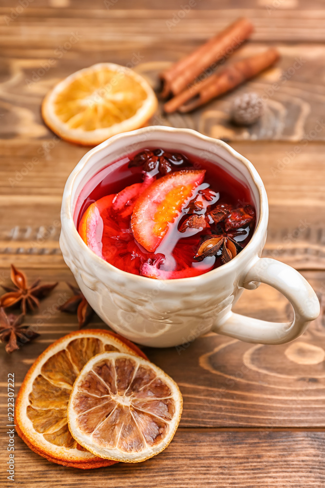 Cup of delicious mulled wine on wooden table