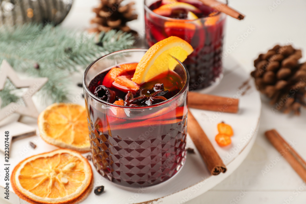 Glasses of delicious mulled wine on white board