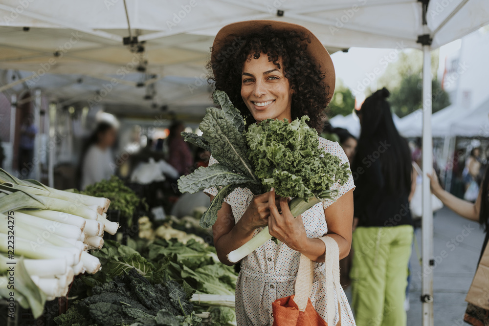 Beautiful woman buying kale at a farmers market