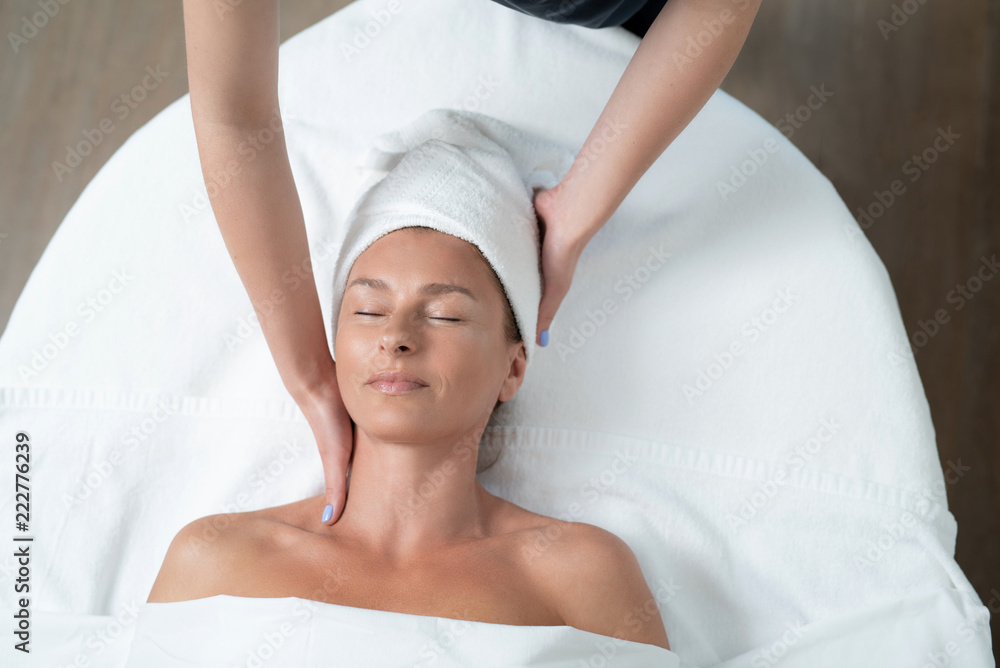 I feel so good. Top view portrait of happy woman with closed eyes lying on massage table during skin