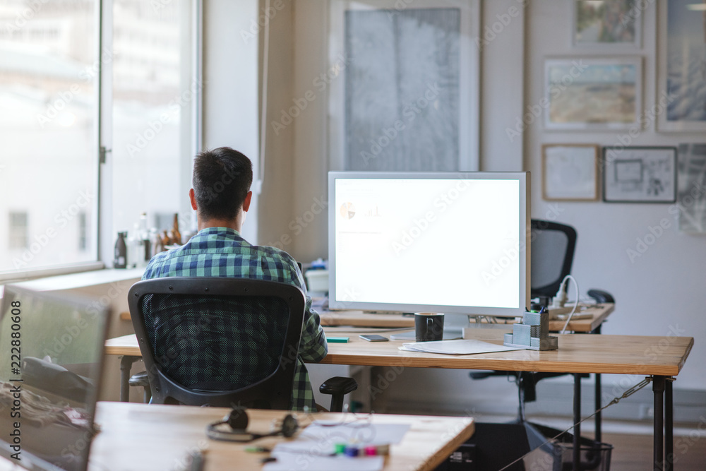 Young designer working late at his desk in an office