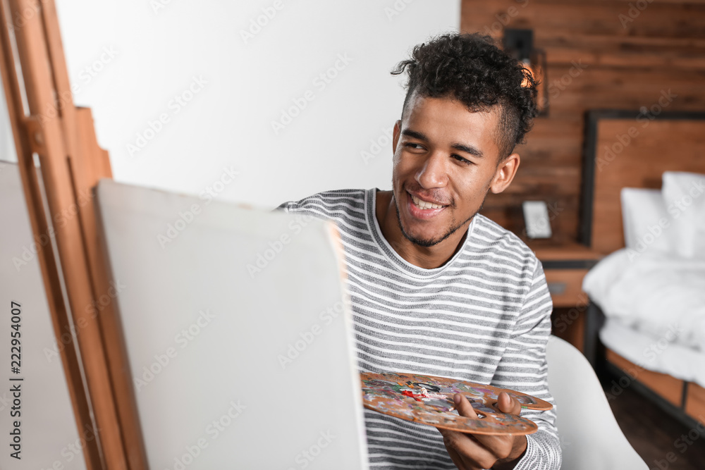 Young African-American artist painting picture at home