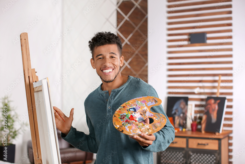 Young African-American artist painting picture at home