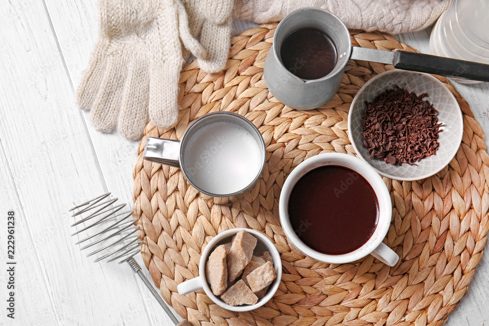 Cezve and cup of hot chocolate with ingredients on wicker mat