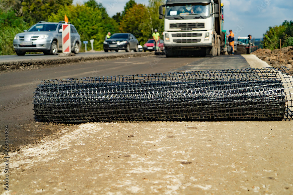 道路工程用钢筋网卷在夏天的高速公路上以汽车为背景铺设