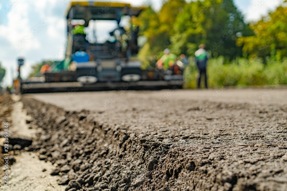 平整地面的道路机械在工人的监督下通过道路。特写