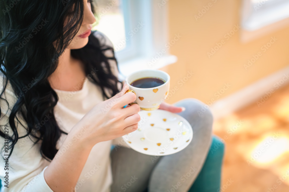 年轻女子在家里的椅子上喝咖啡