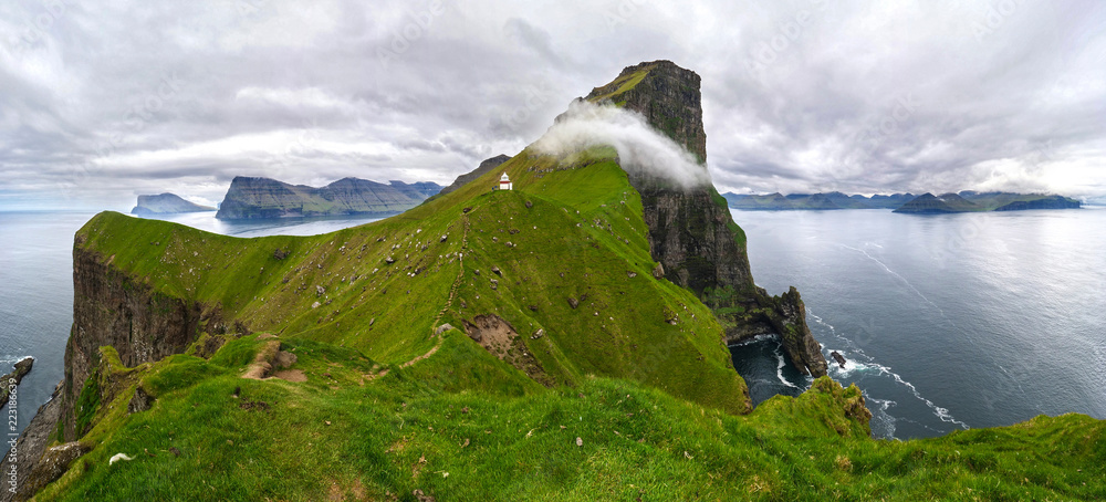 岩石峭壁和建在长满青草的小山上的白色灯塔的美景。