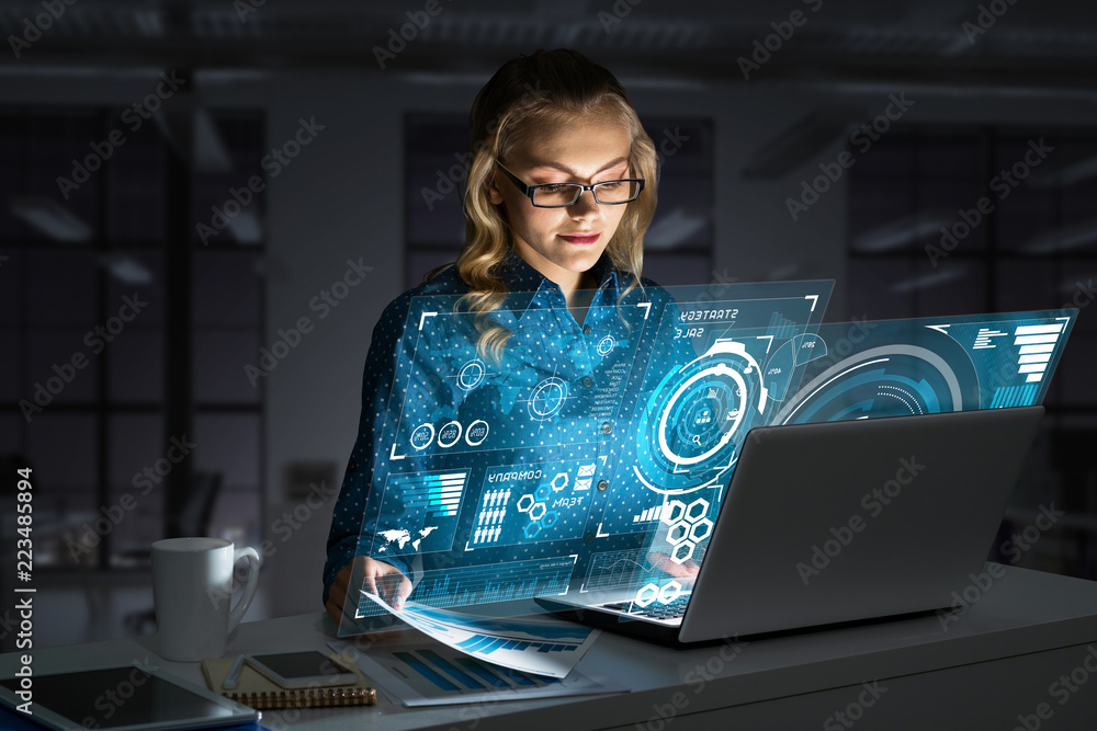 Beautiful blonde working on laptop and infographs out of screen. Mixed media