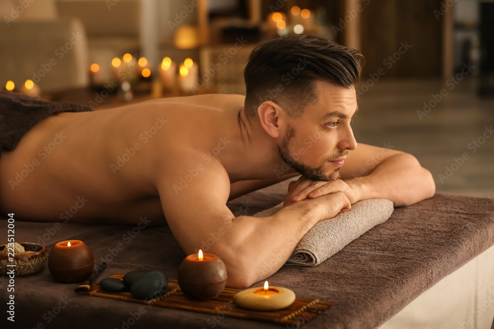 Young man relaxing on massage table in spa salon