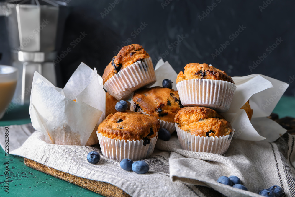 Tasty blueberry muffins on color table