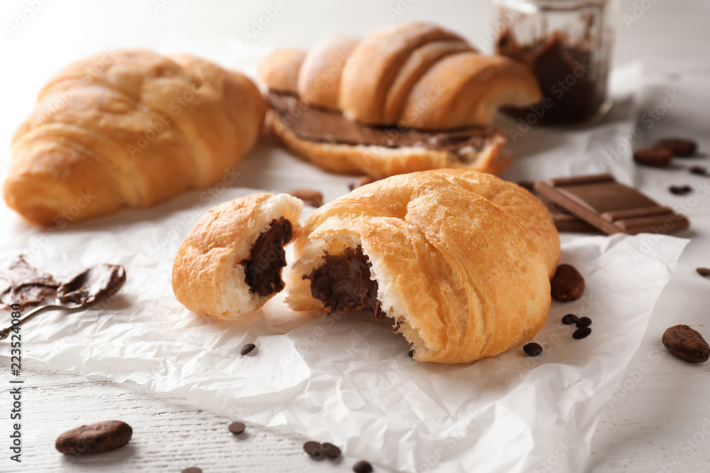 Tasty croissant with chocolate on white table