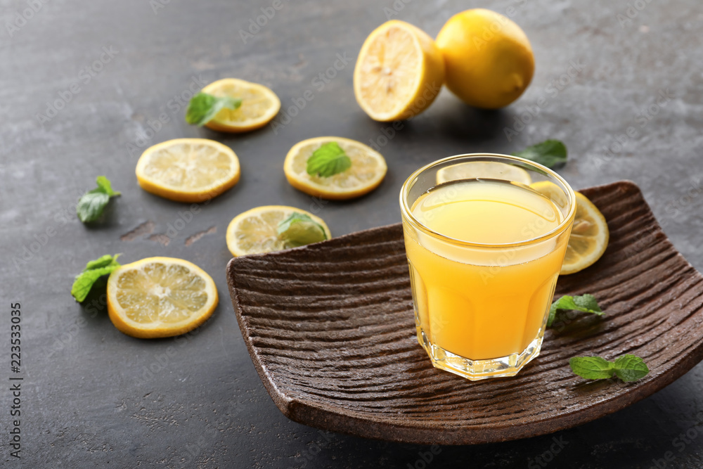 Glass of fresh lemon juice on grey table