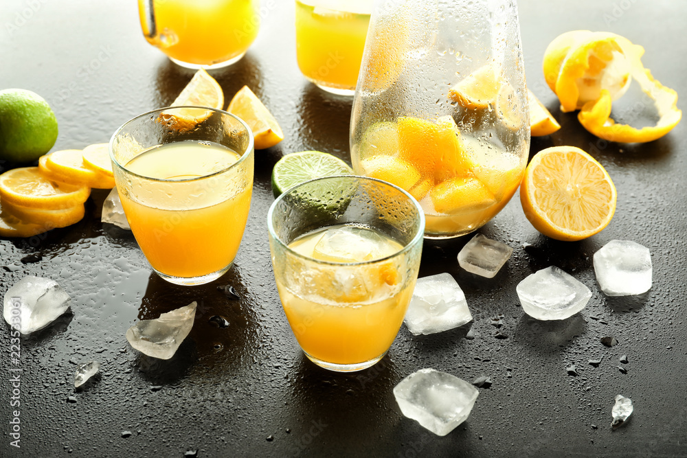 Glasses of fresh lemon juice with ice cubes on dark table