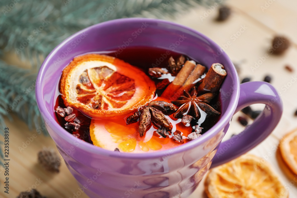 Cup of delicious mulled wine on wooden table