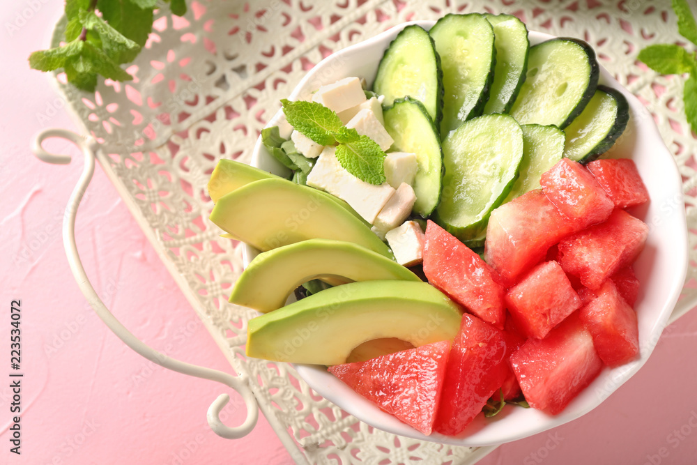 Tasty salad with watermelon, feta and vegetables in bowl on vintage tray