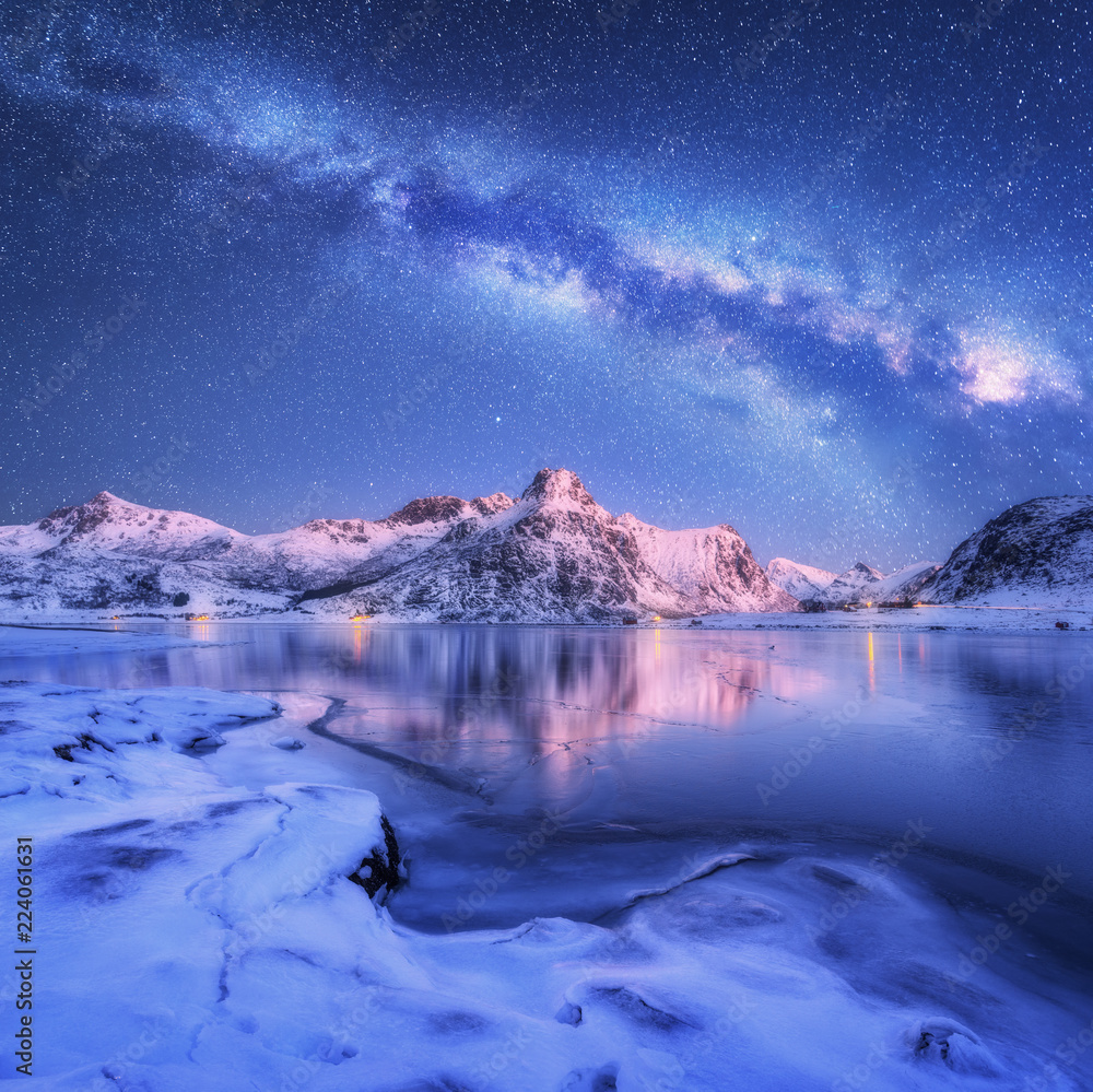 北罗弗敦群岛冬季夜间冰冻海岸和白雪皑皑的山脉上方的银河系