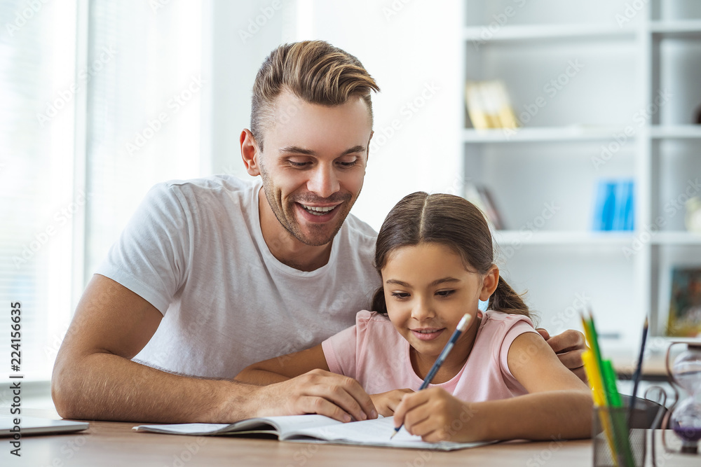 The happy man and a girl doing homework at the desk