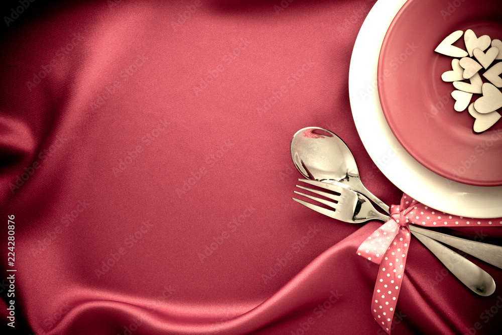 red heart shape with White empty plate with fork and spoon on red silk fabric for love dinner concep