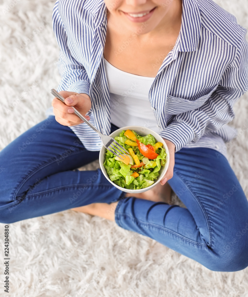 年轻女性在家吃新鲜沙拉。健康食品理念