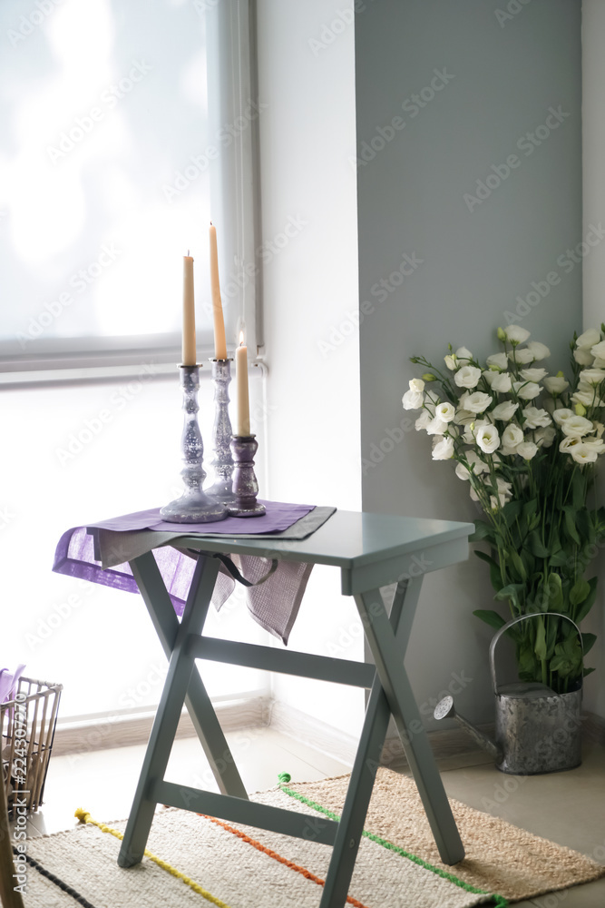 Cozy place for rest with candles on table near window in kitchen