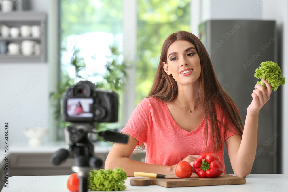 Young female food blogger recording video in kitchen