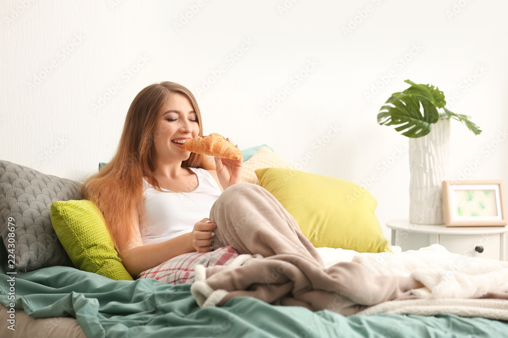 女人在卧室里吃美味的羊角面包