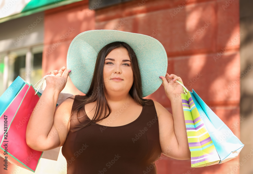 城市街服装店附近的超重妇女拿着购物袋