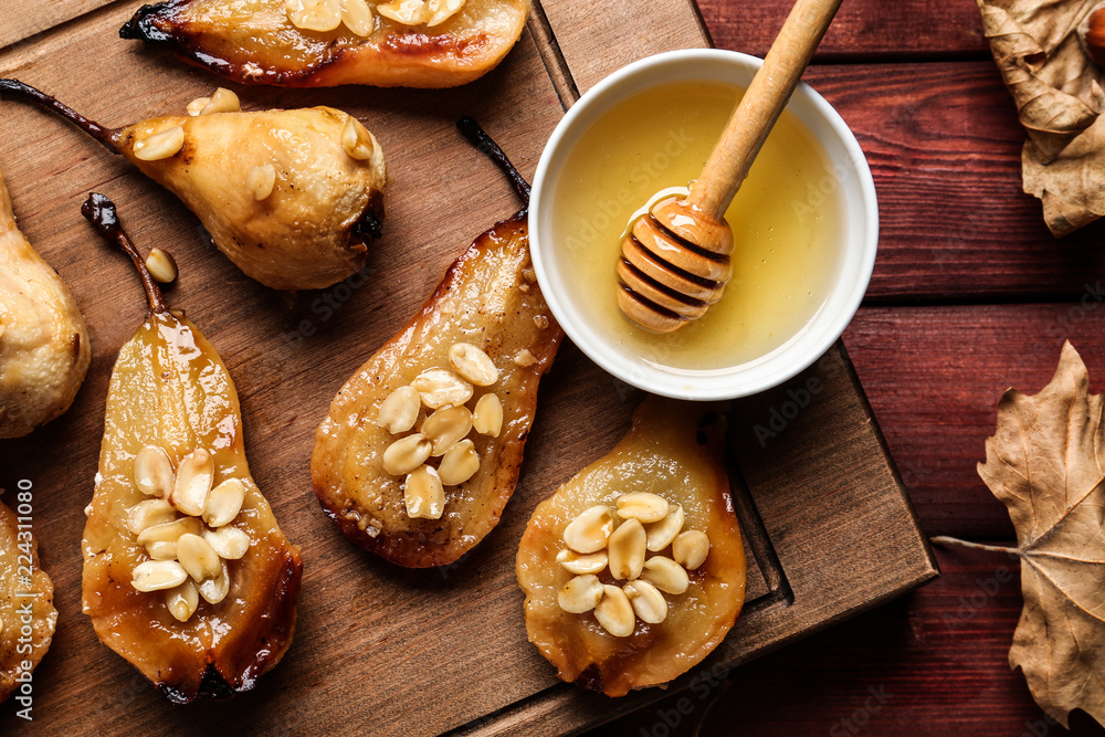 Wooden board with baked pears, peanuts and honey on table