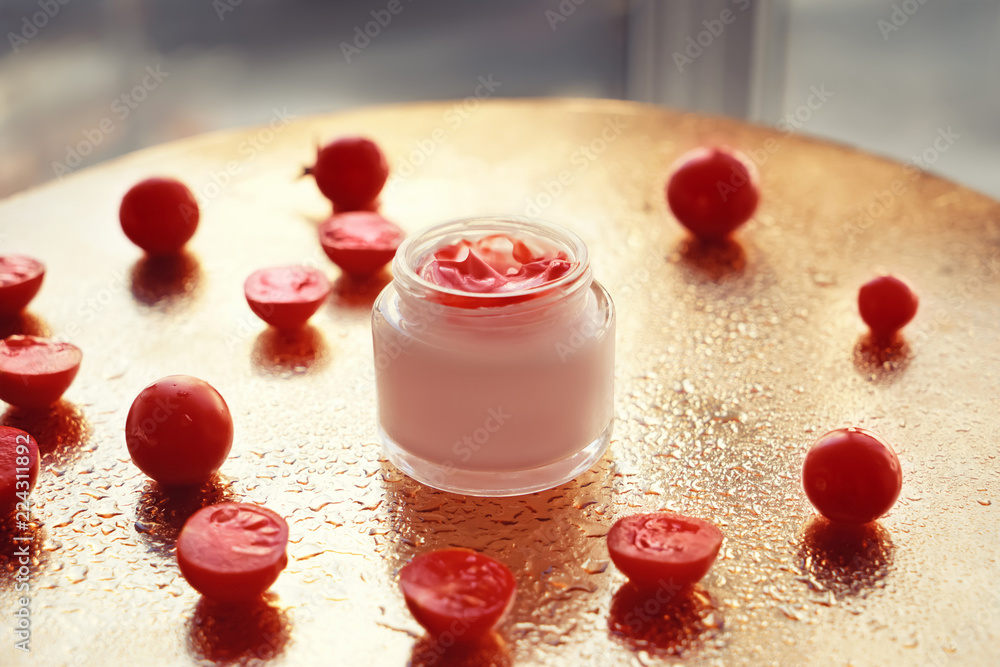 Jar with body cream and tomatoes on golden table