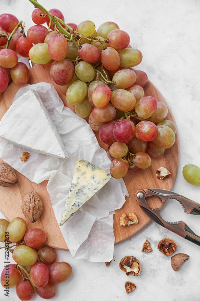 Ripe juicy grapes with cheese and walnut on wooden board