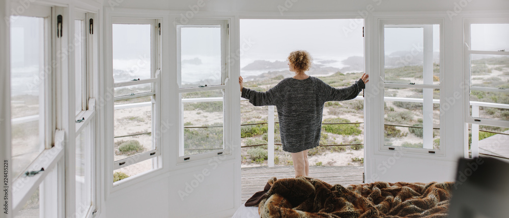 一名女子从海滩小屋向外看的后视图