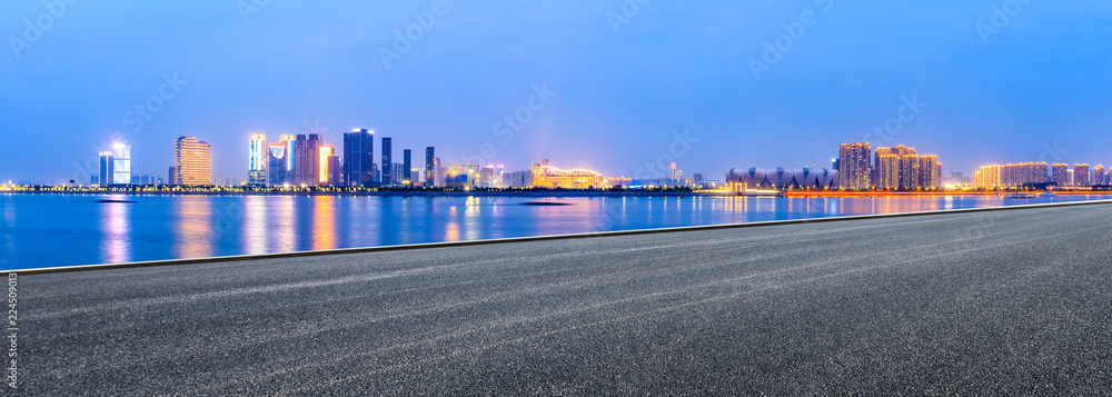 Urban asphalt road and modern buildings with river in Hangzhou at night