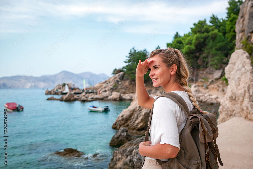 背着背包的旅游女性，看着海边，在旅行中发现