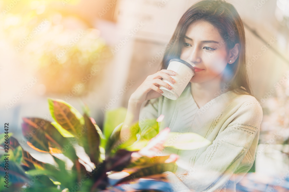 美丽的亚洲女人早上在咖啡馆的橱窗附近享受热饮生活方式理念