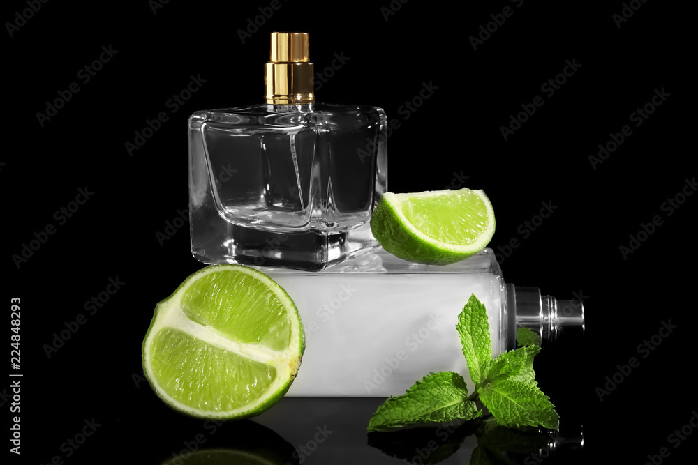 Bottles of fresh perfume, lime and mint on black background