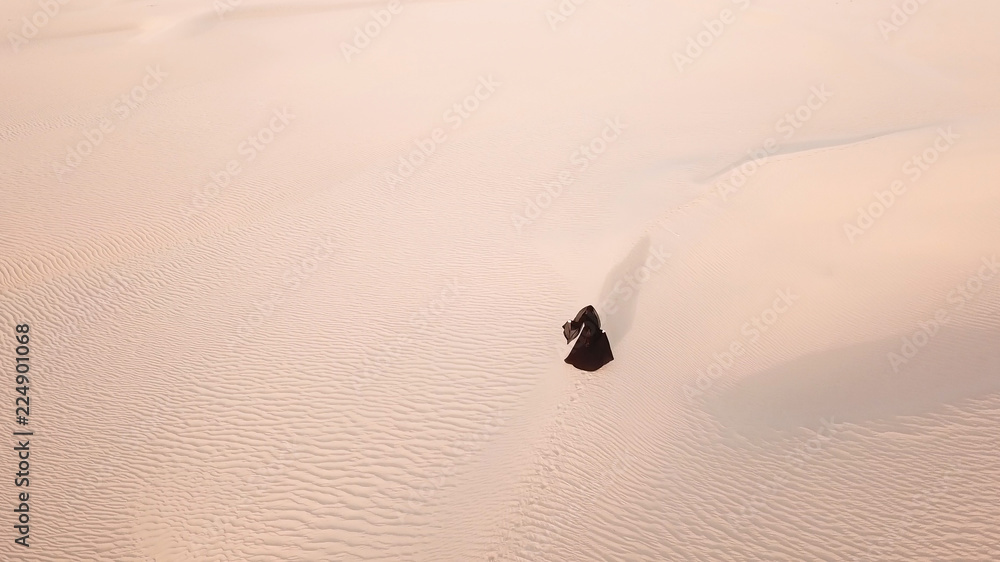 A woman in abaya (United Arab Emirates traditional dress) walking on the dunes in the desert during 