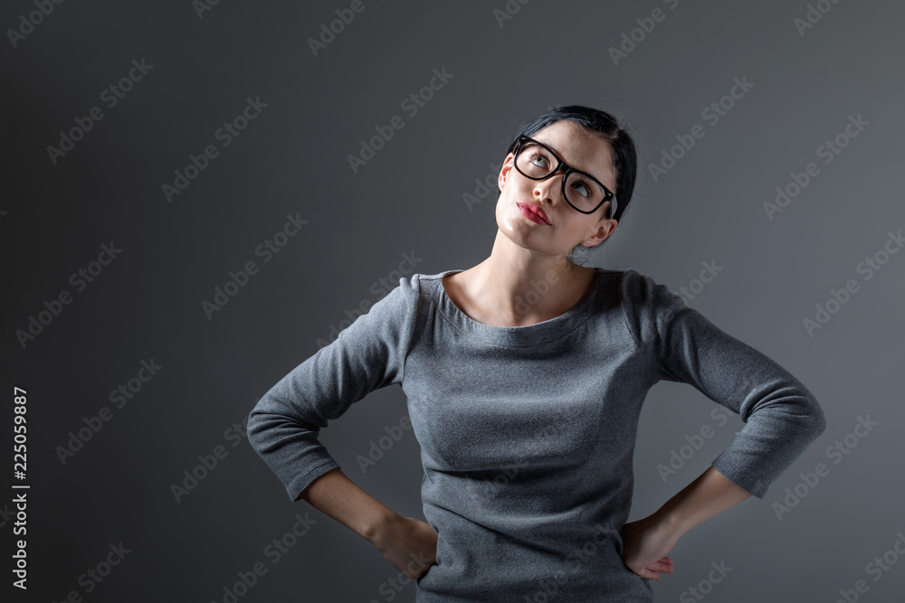 年轻女子在坚实的背景上摆出深思熟虑的姿势