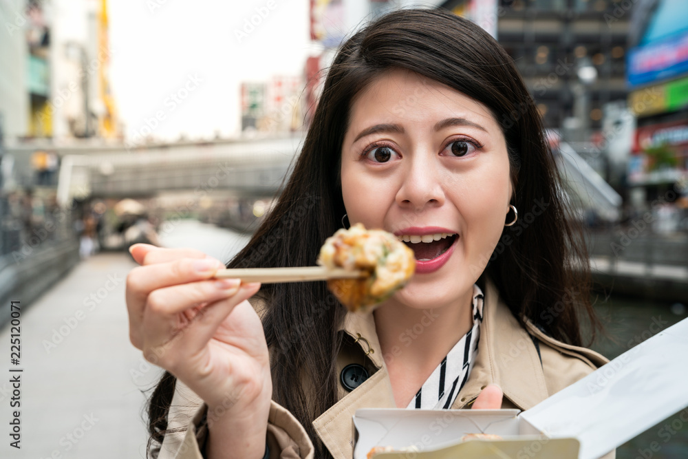 游客用筷子吃takoyaki