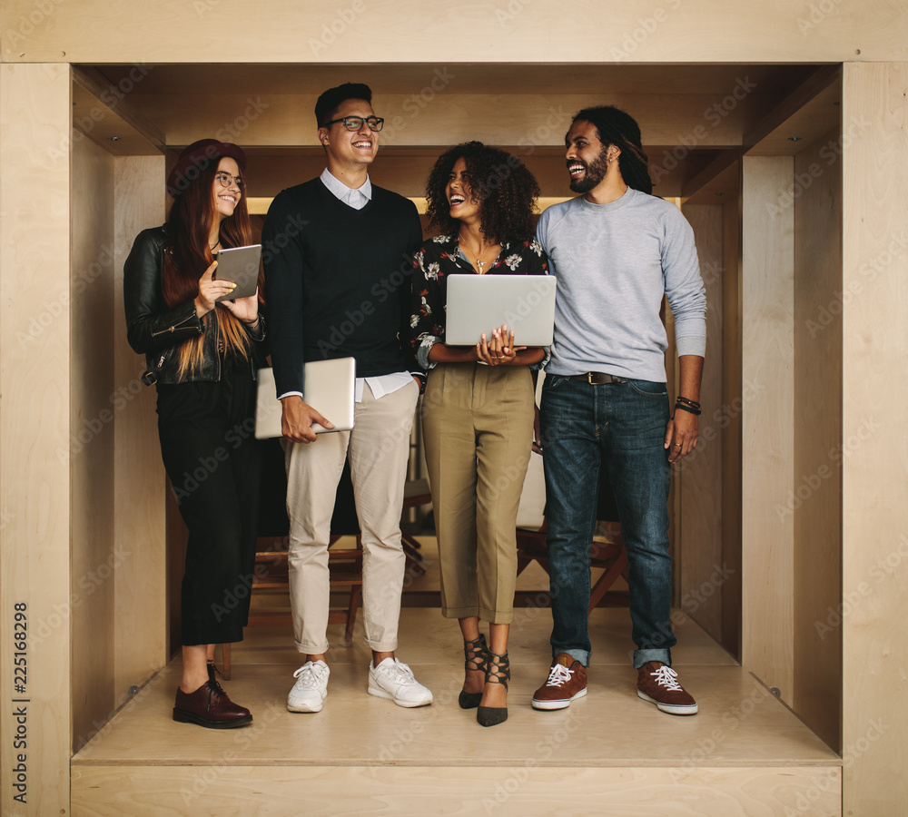 Business colleagues standing in office with laptops and tablet