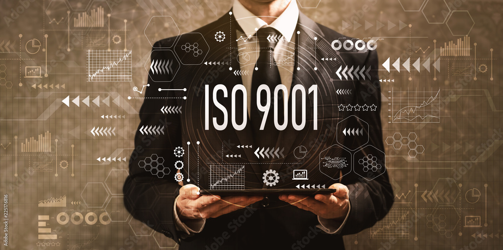 ISO 9001 with businessman holding a tablet computer on a dark vintage background