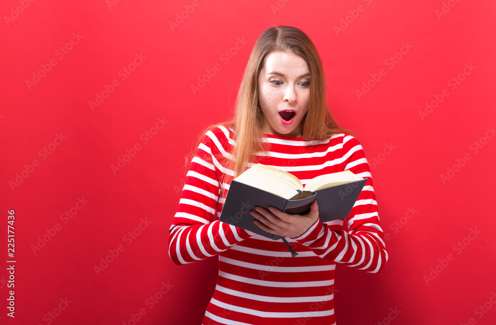 Young woman with a book on a red background