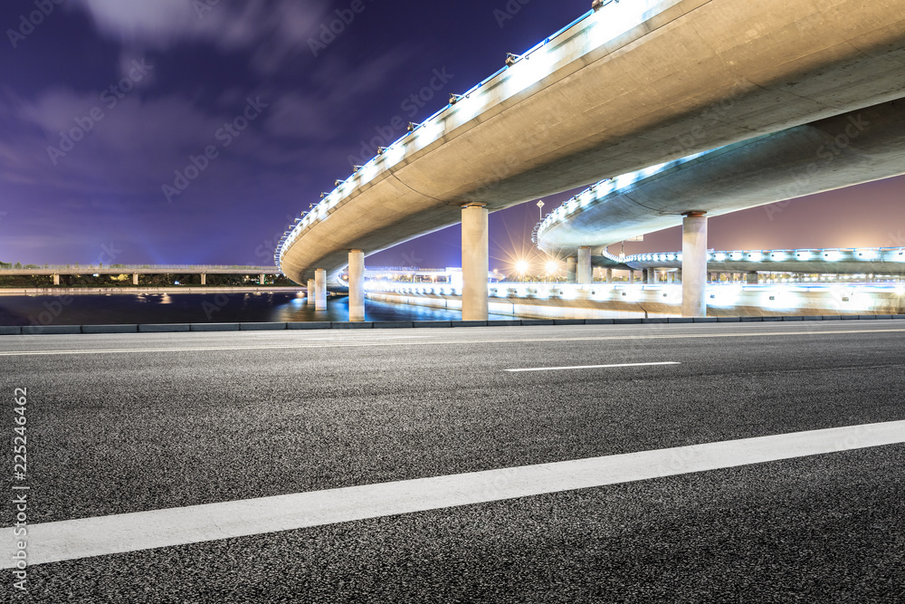 Asphalt road and modern bridge building scenery at night