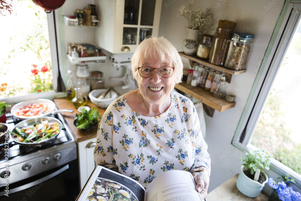 Happy elderly woman reading a cookbook