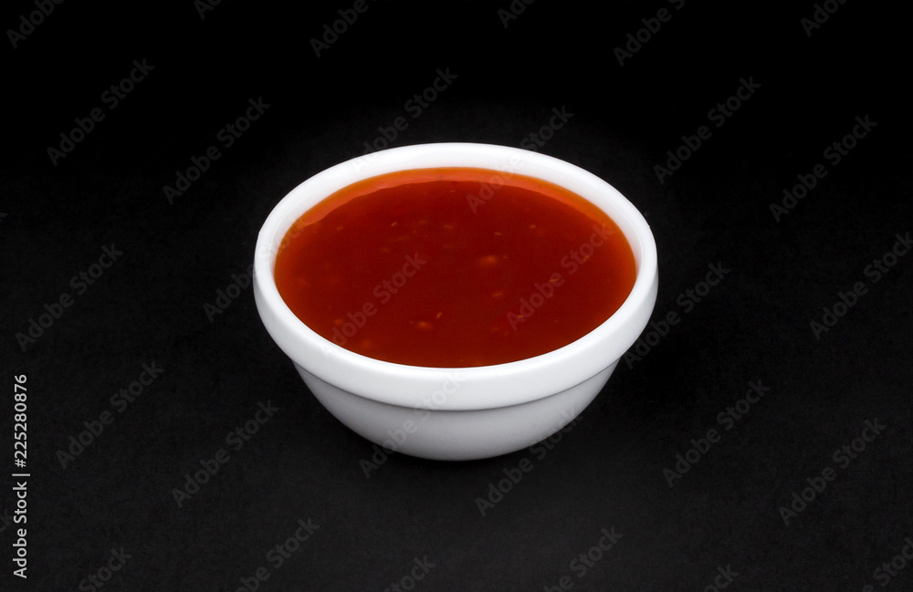 Hot chilli sauce in bowl isolated on black background