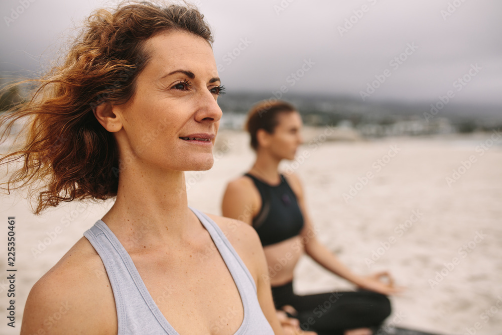 Fitness women doing yoga sitting on the beach