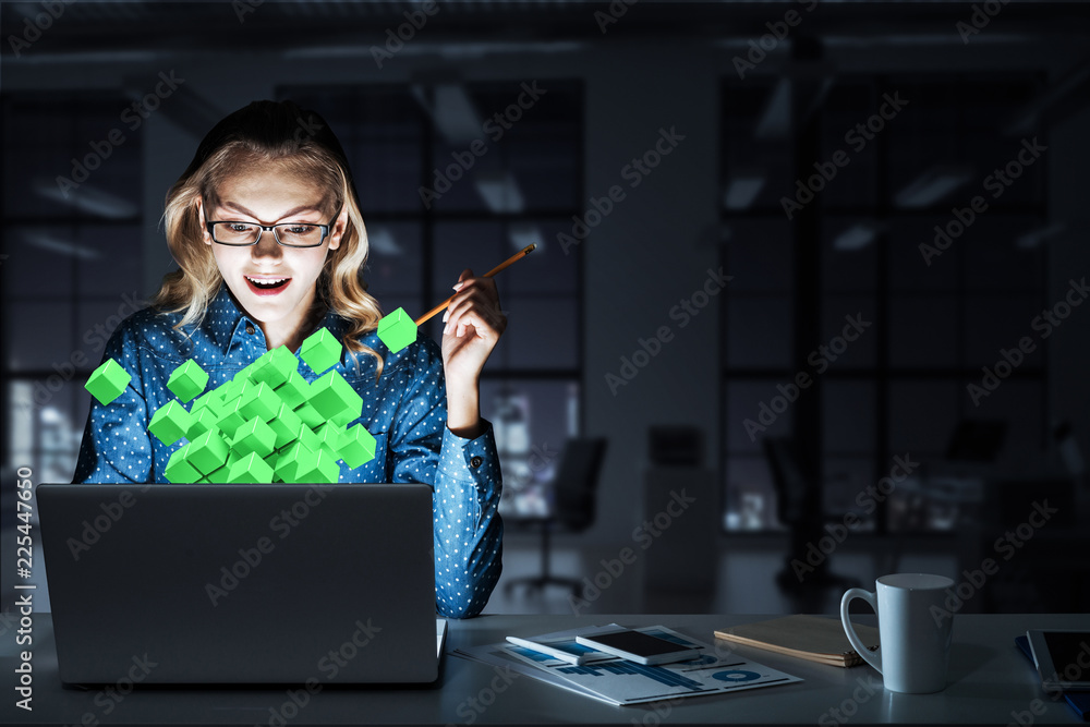 Attractive blonde wearing glasses in dark office using laptop. M