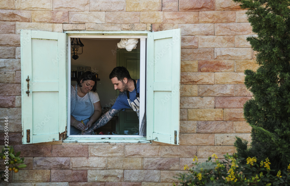 Man and woman cooking viewed through a window