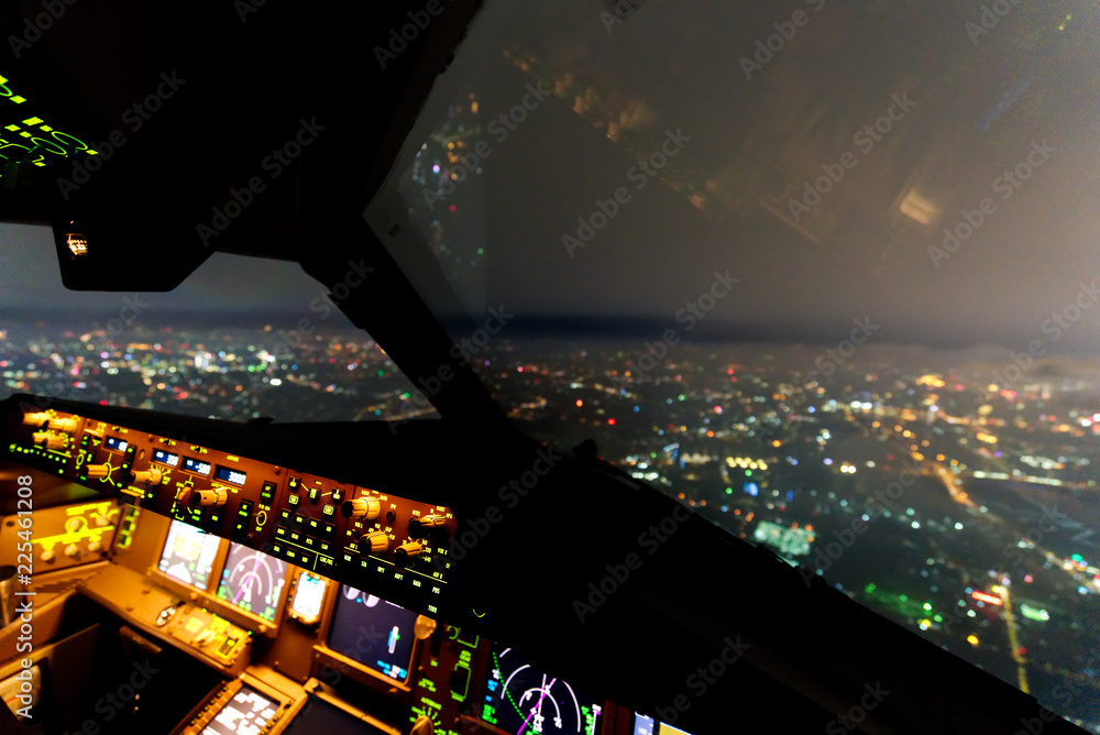 夜间在城市上空飞行时，商用飞机驾驶舱内。窗外可以看到b