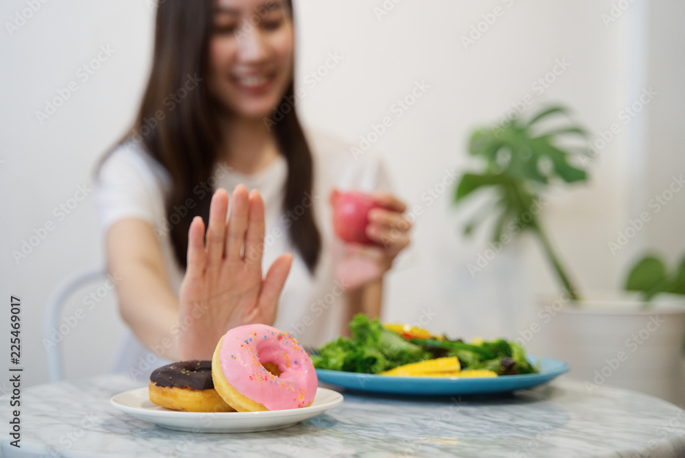 年轻女孩为了健康而节食。特写女性用手推垃圾食品